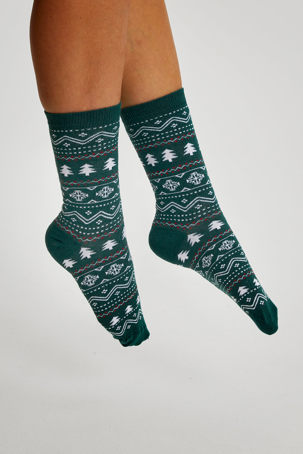 Een paar groene kerstsokken met kerstbomen erop.