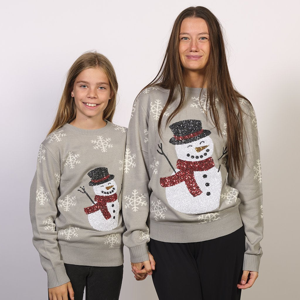Una donna e un bambino che indossano un maglione natalizio grigio con un pupazzo di neve.