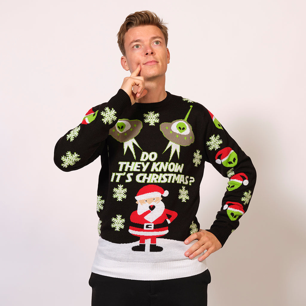 En mand iført en julesweater pyntet med en julemand, rumvæsner og ufoer.