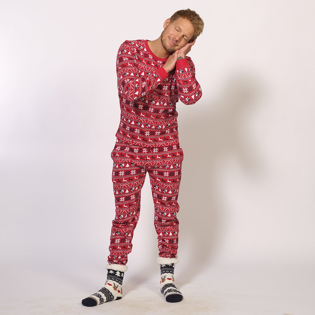 Un uomo addormentato che indossa un pigiama rosso con motivi natalizi.