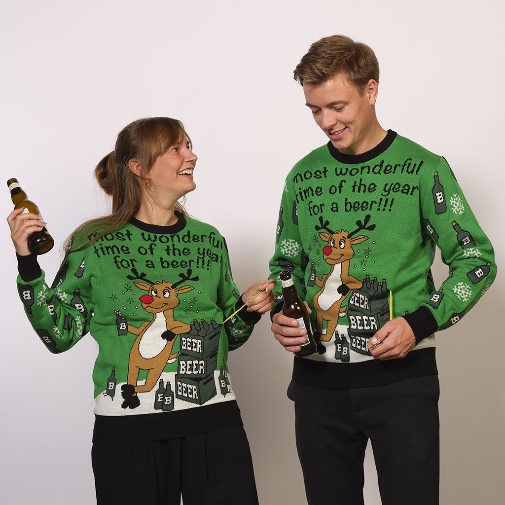 Una coppia che indossa un Una coppia che indossa un maglione verde di Natale con la citazione  “The most wonderful time of the year for a beer” in inglese.