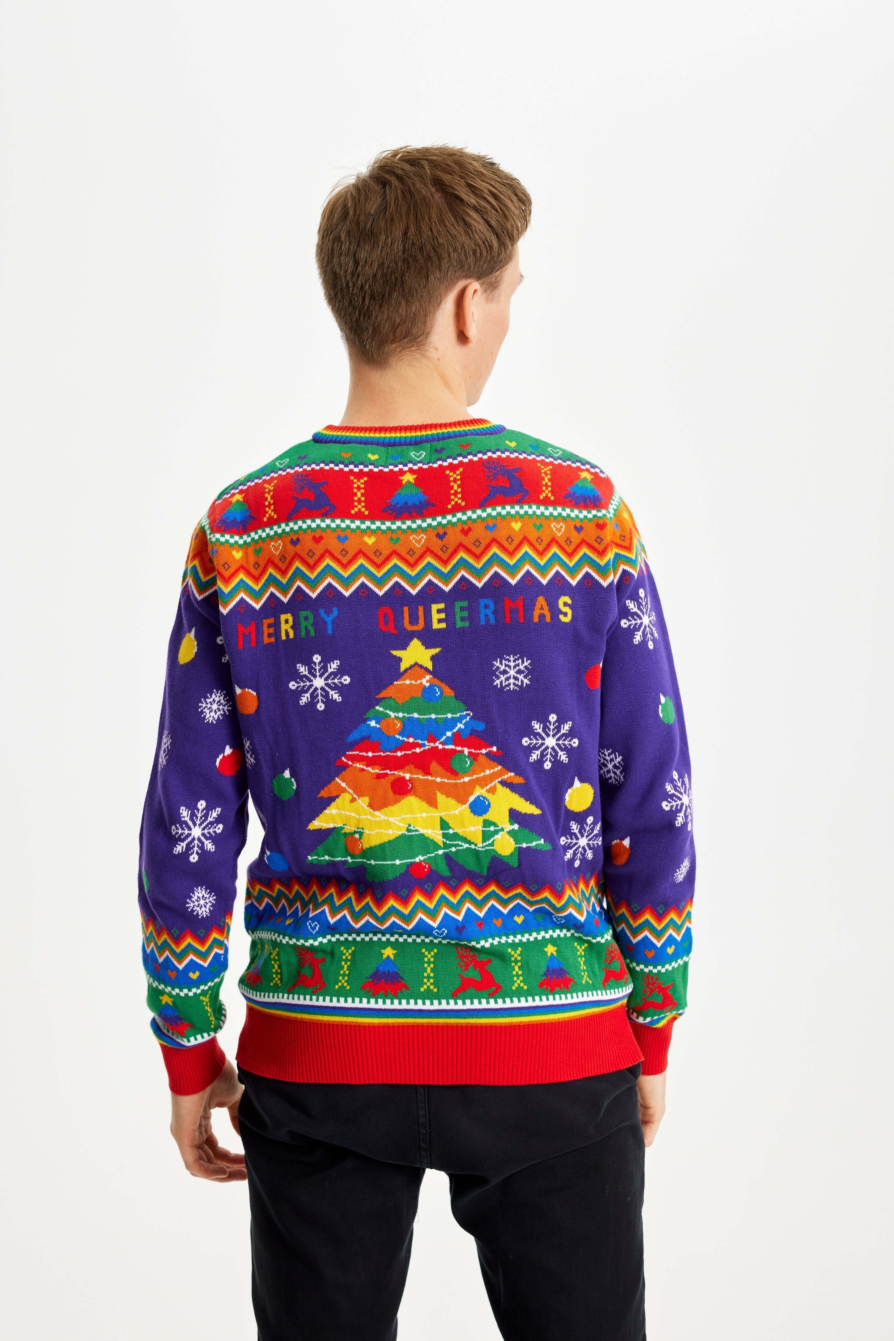 Un uomo posa di spalle indossando un maglione natalizio color arcobaleno con la scritta 