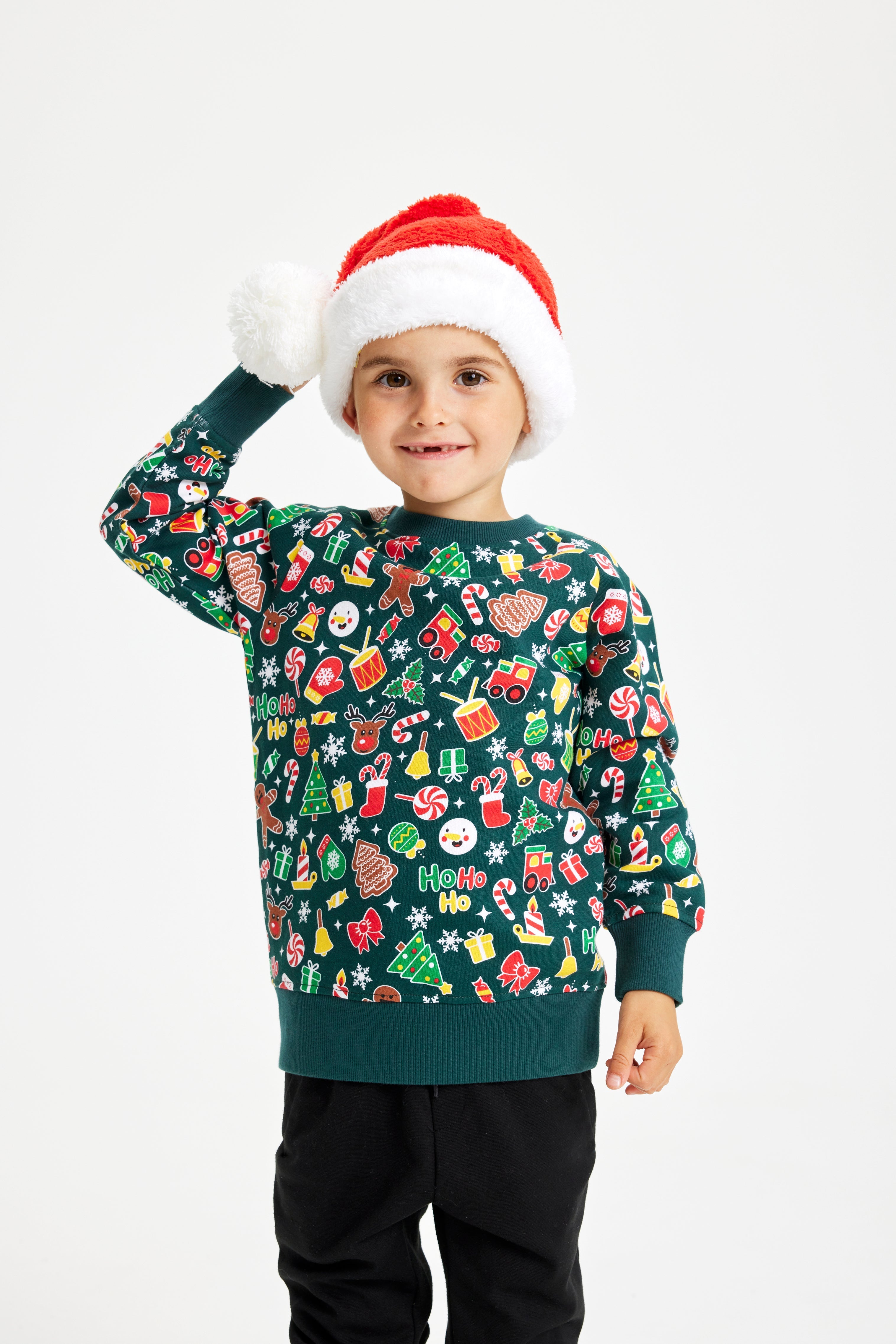 Un bambino posa indossando un maglione natalizio verde.