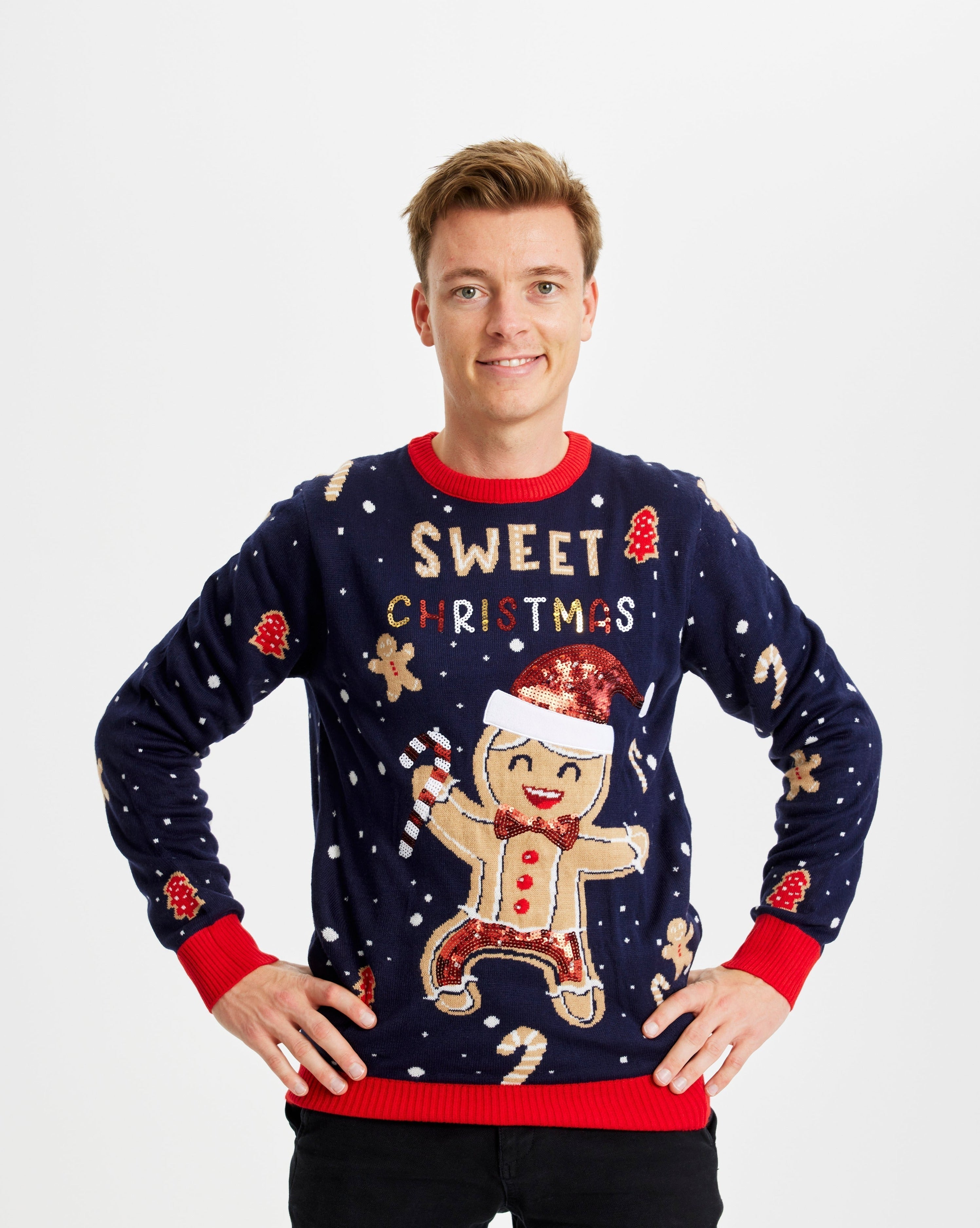 Un uomo sorridente che indossa un maglione natalizio blu con una torta e delle luci.