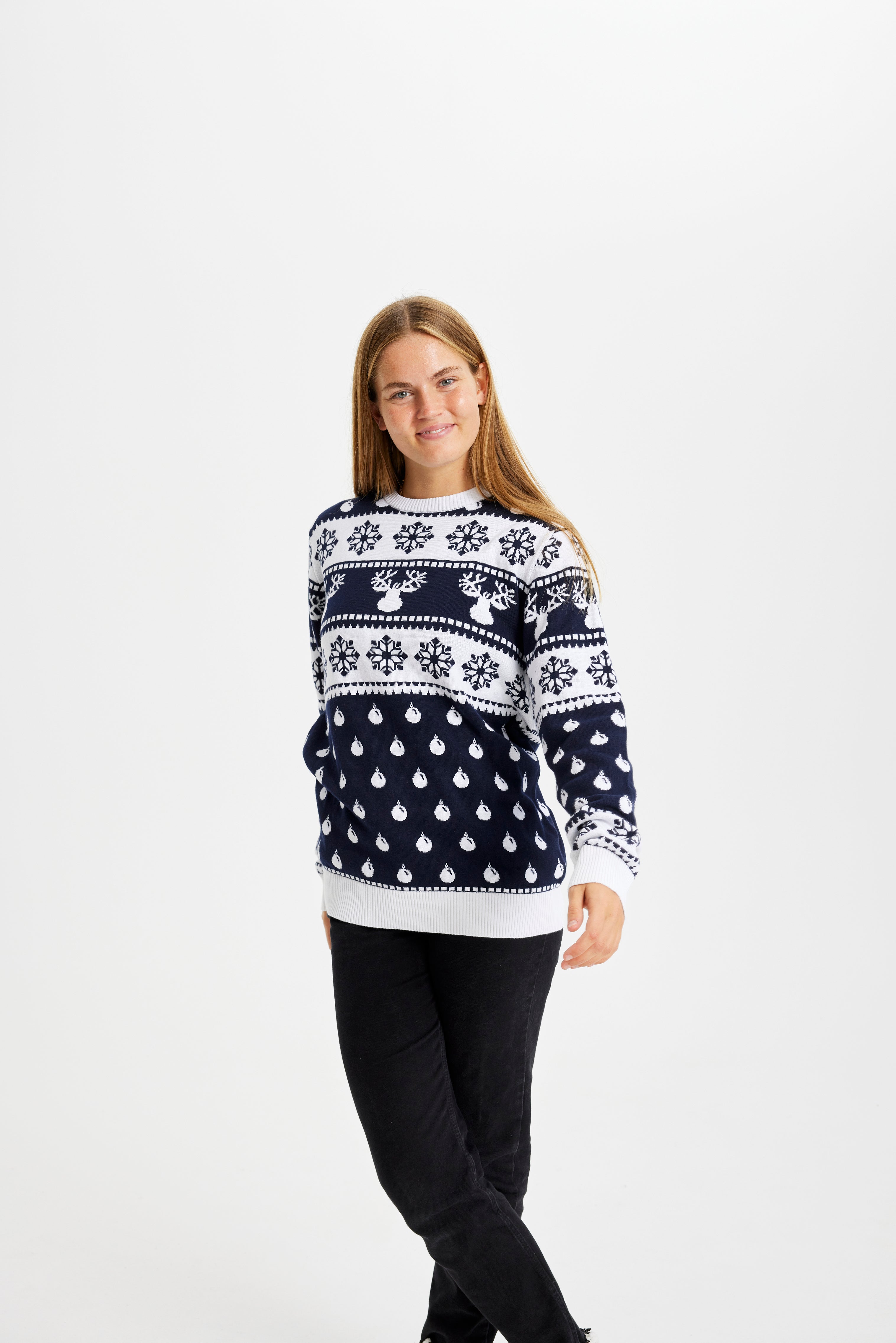 Una donna in posa che indossa un maglione natalizio bianco e blu.
