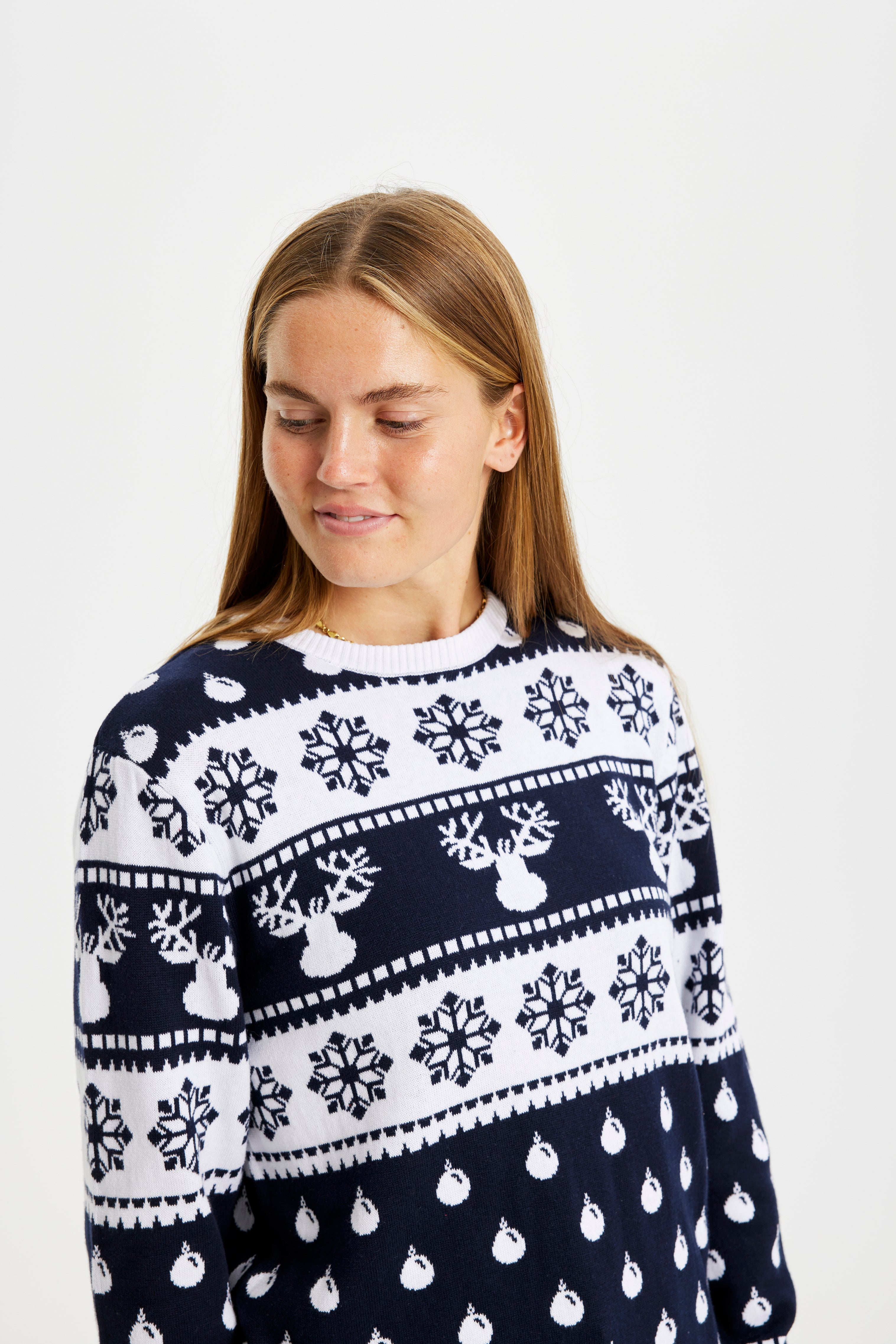 Una donna sorridente che indossa un maglione natalizio bianco e blu.