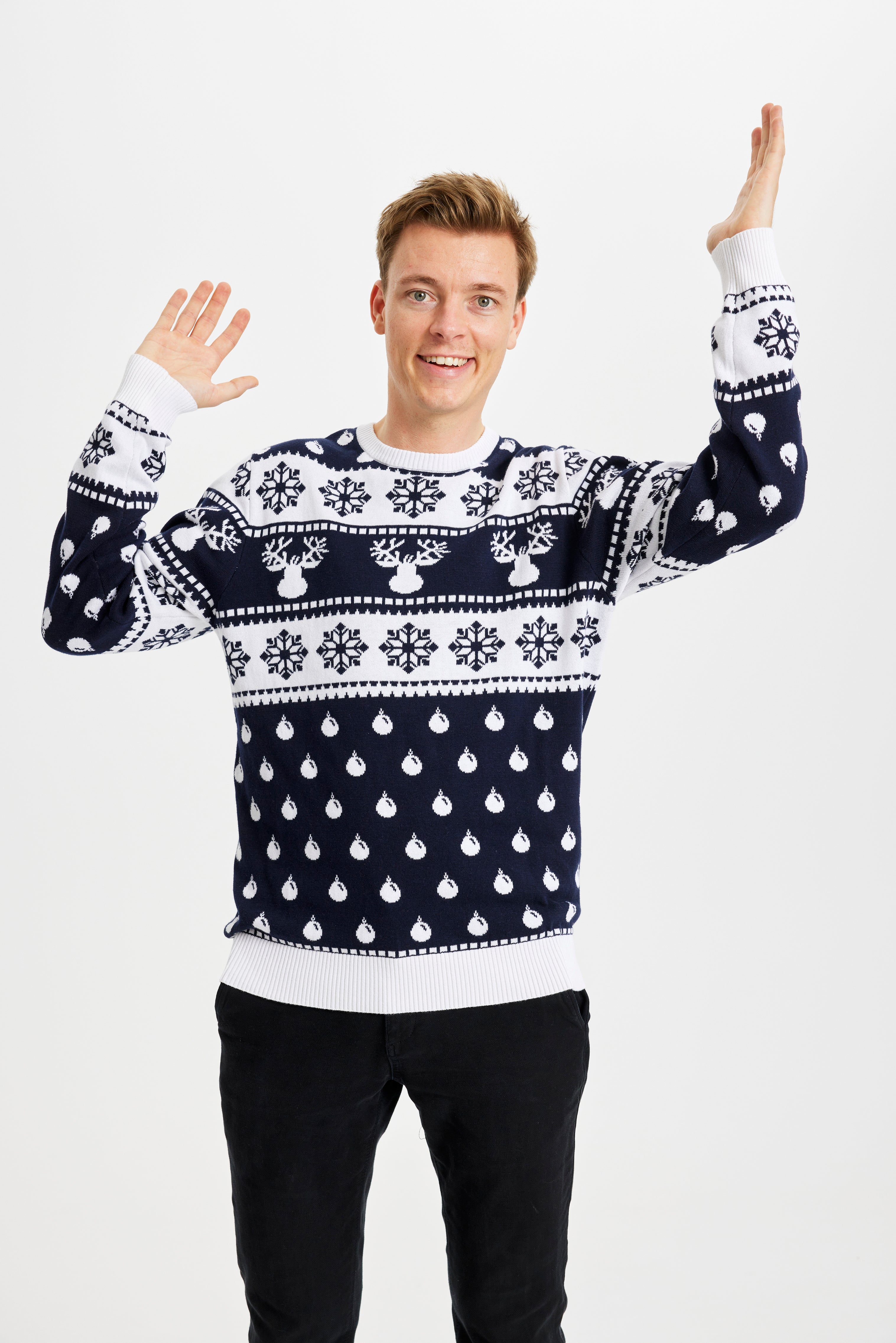 Un uomo sorridente che indossa un maglione natalizio bianco e blu.