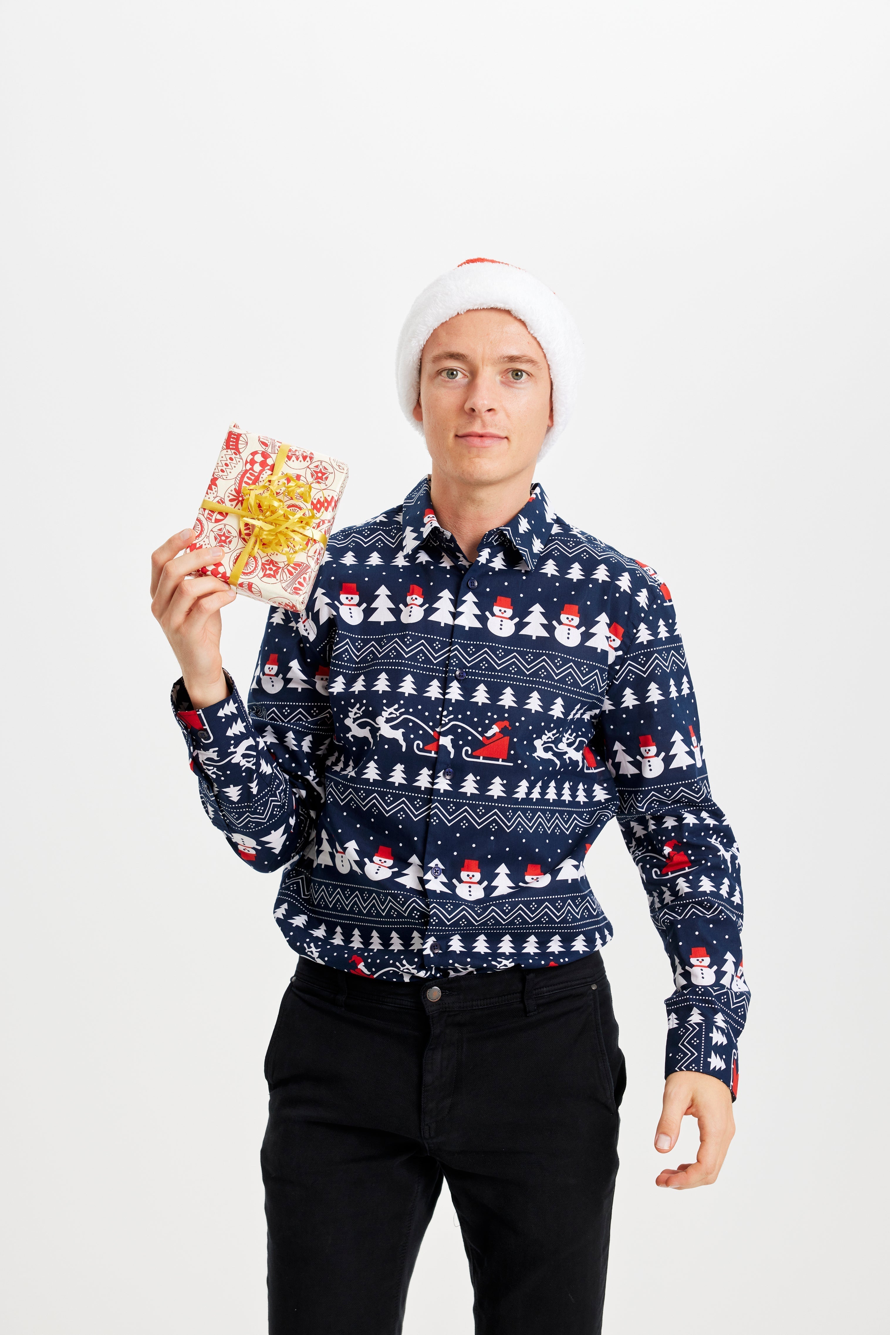 Un uomo con un regalo che indossa un maglione natalizio blu.