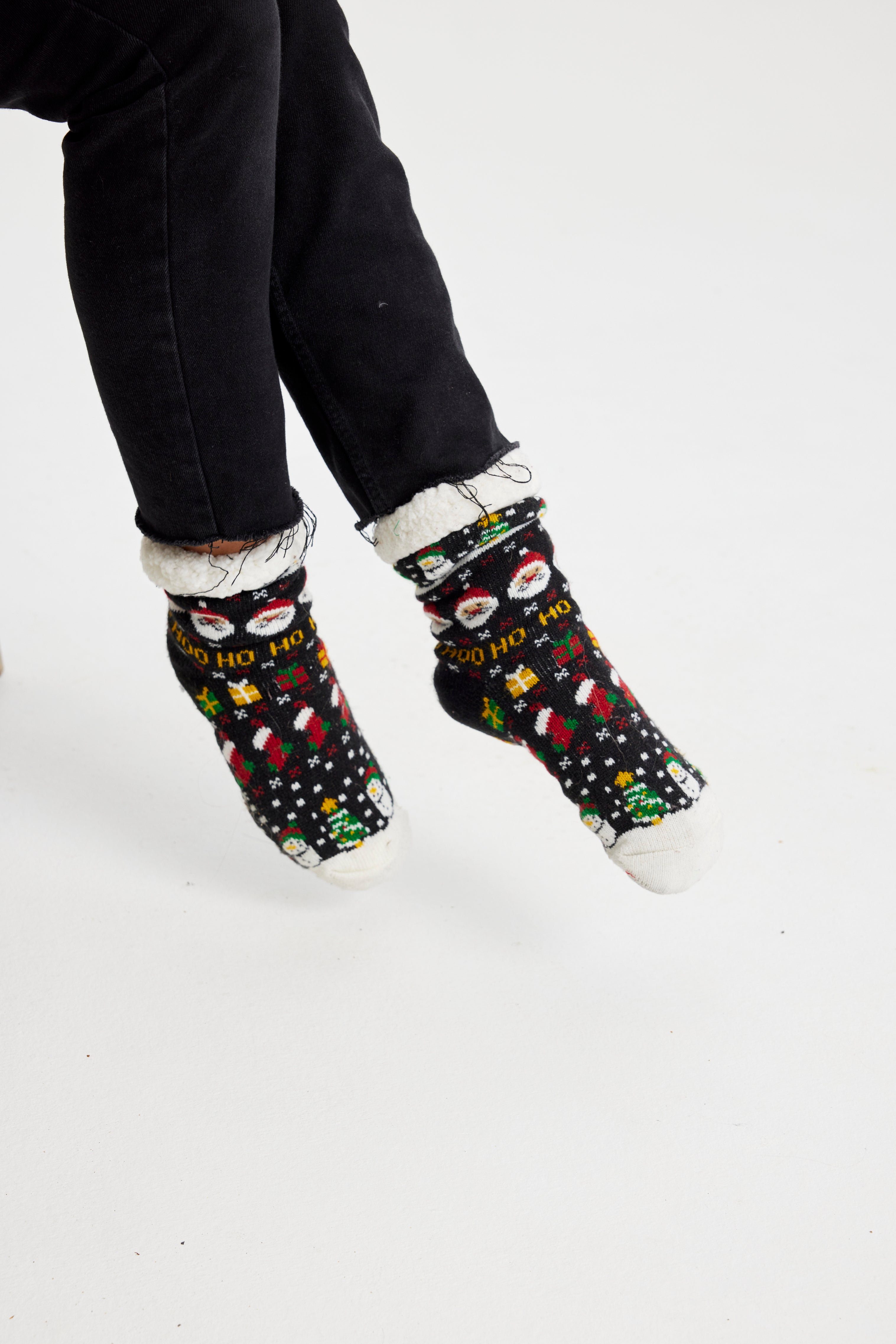 Un paio di piedi con calzini natalizi neri.