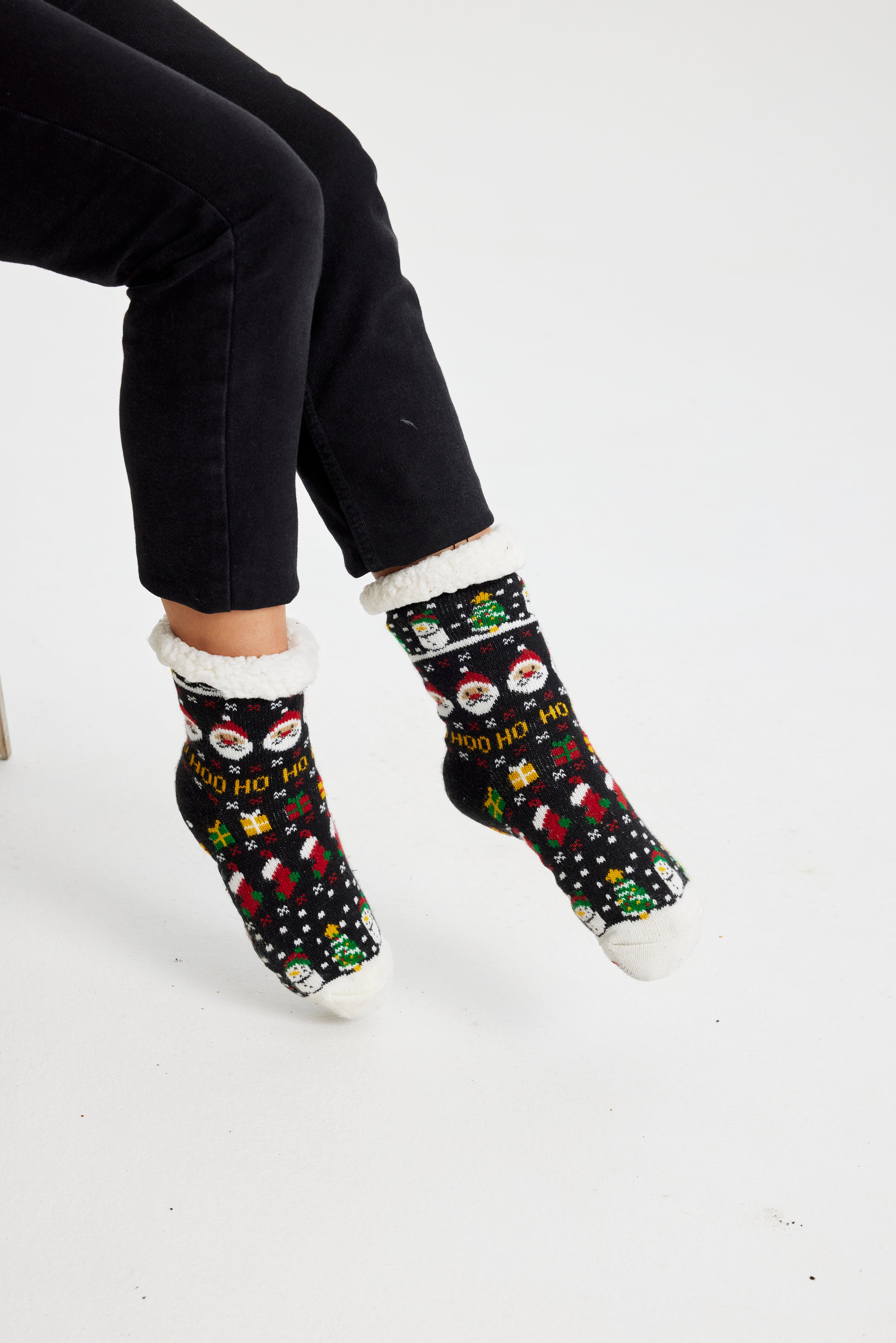 Un paio di piedi con calzini natalizi neri.