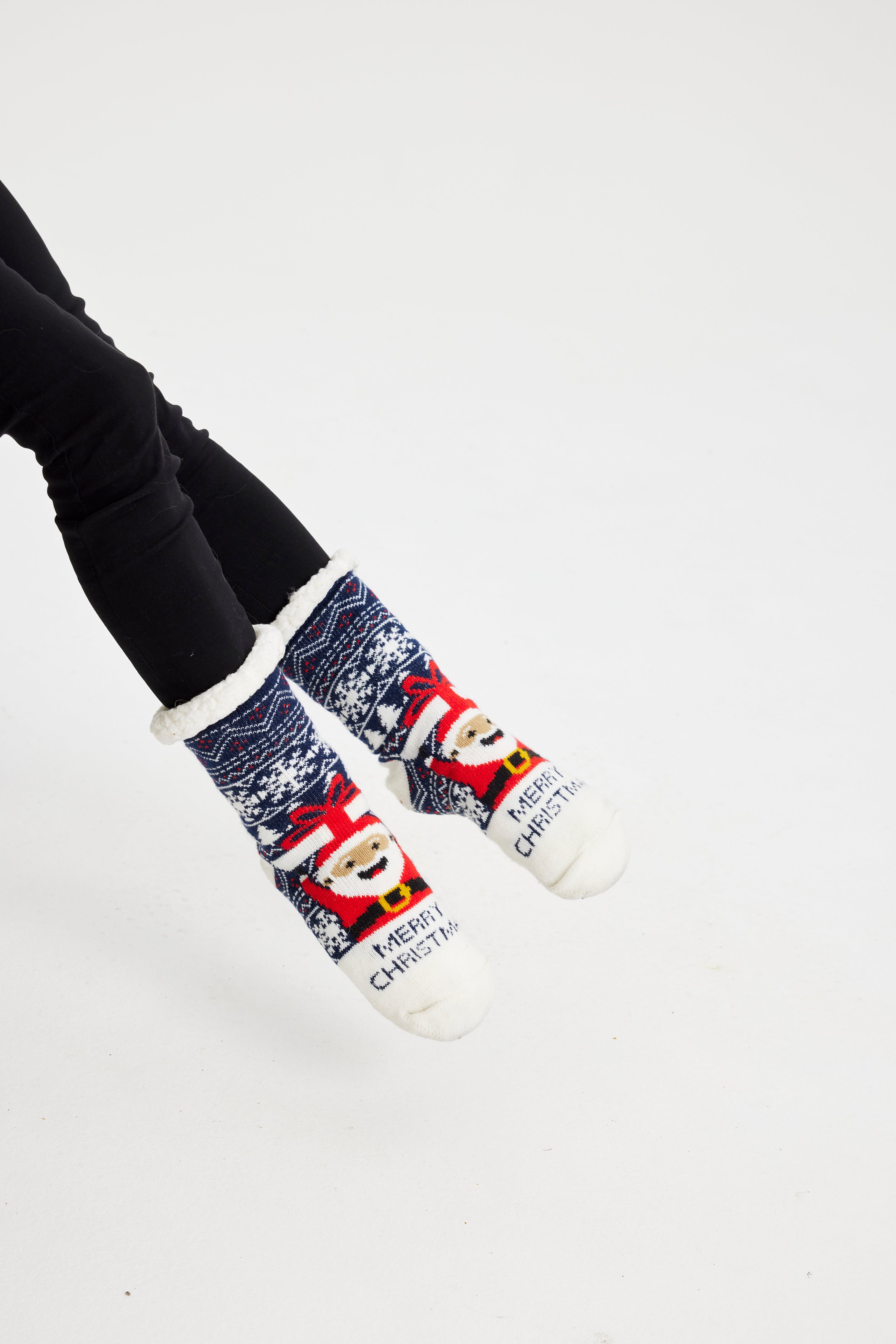 Un paio di piedi che indossano calzini di Natale bianchi, rossi e blu.