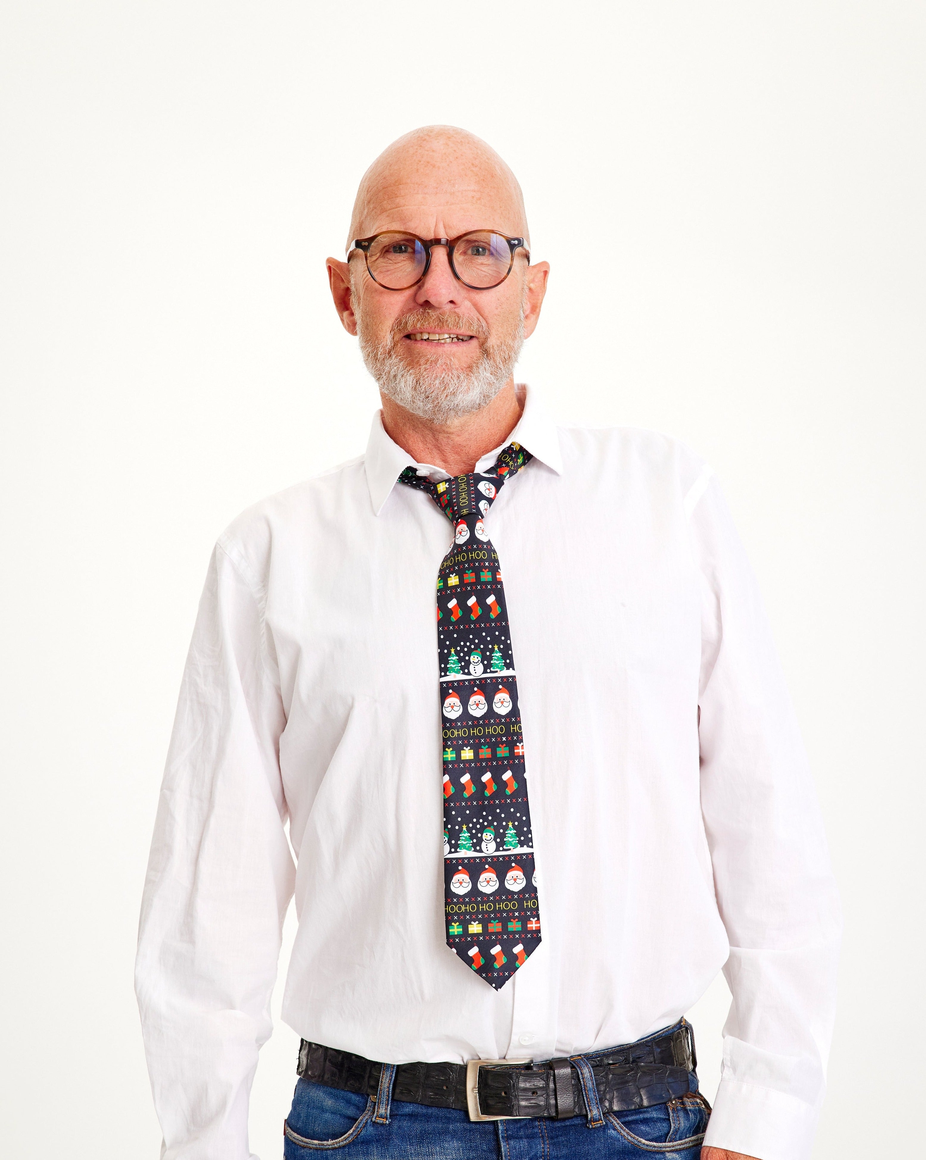 Un uomo sorridente in camicia bianca e cravatta natalizia.