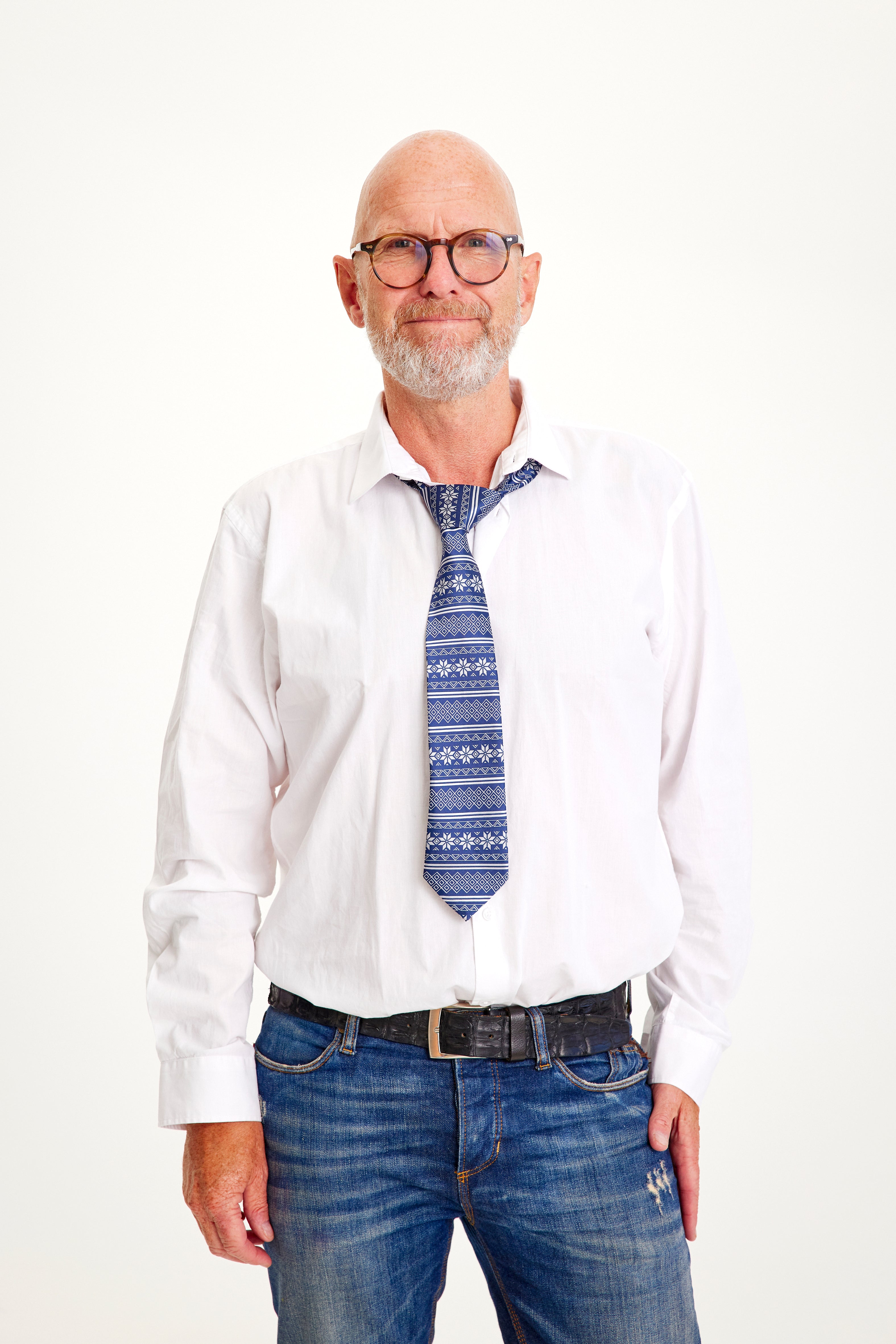 Un uomo sorridente in camicia bianca e cravatta natalizia.