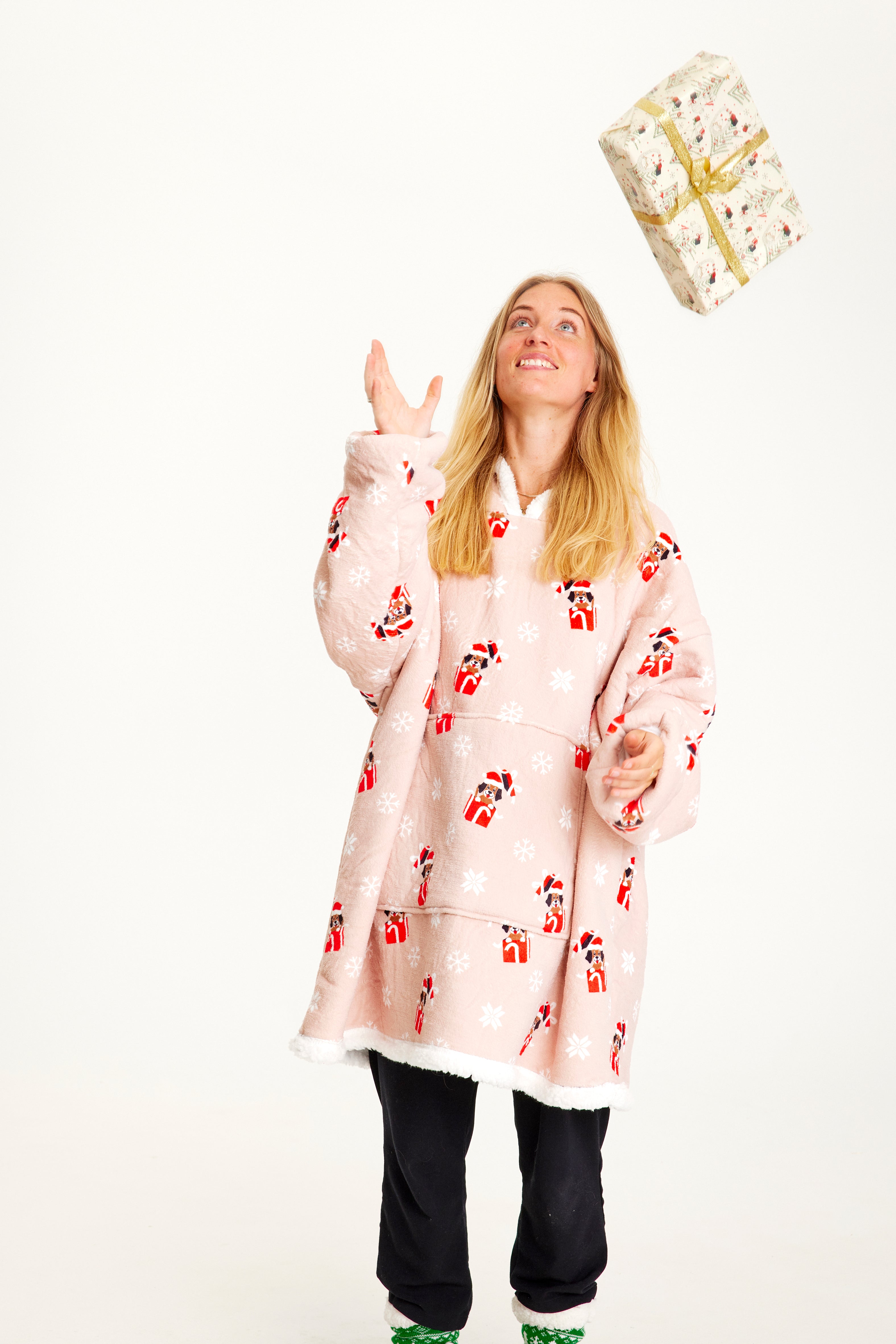 Una donna con un regalo che indossa una felpa natalizia rosa con i cani.