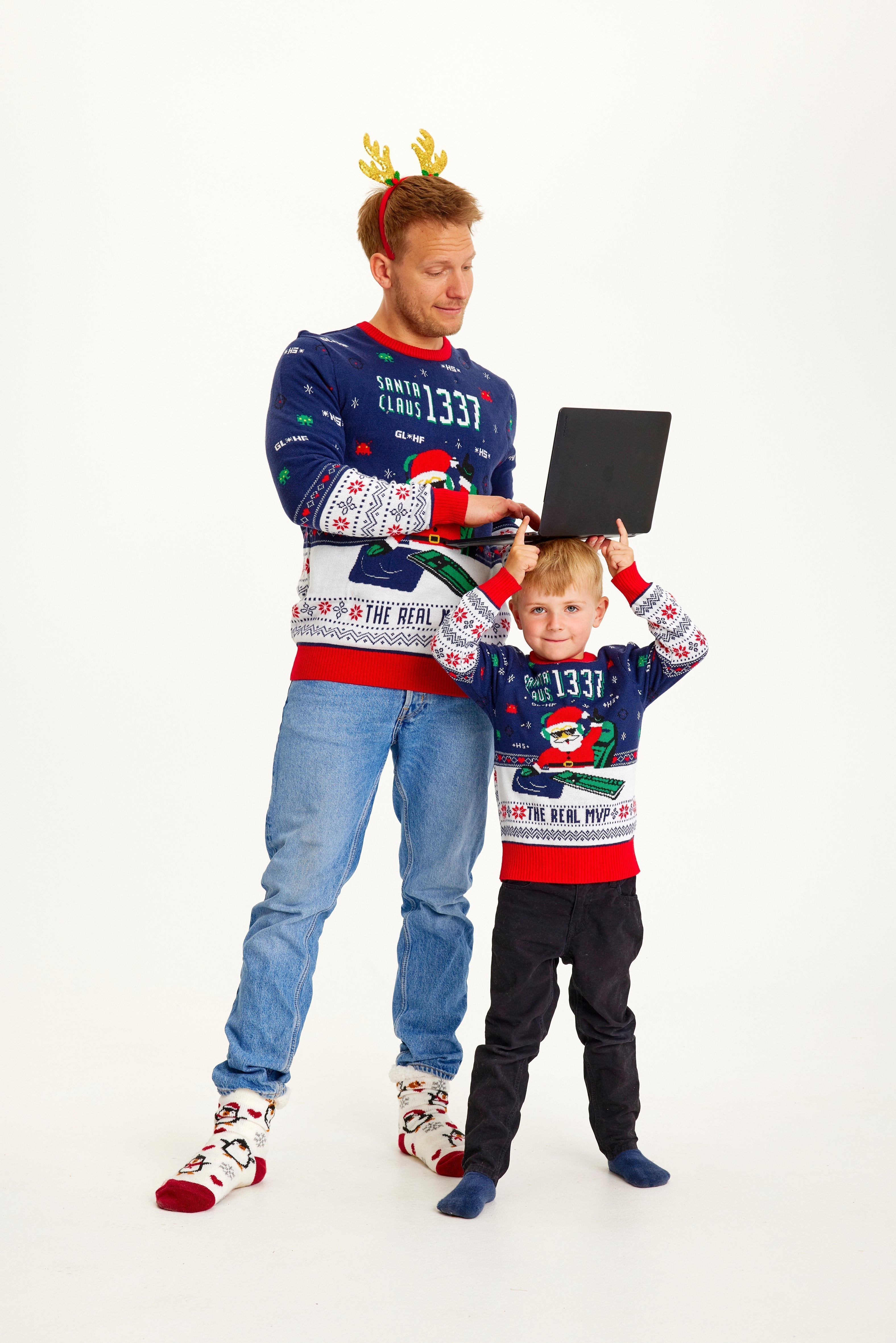 Un bambino e un uomo che indossano un maglione natalizio blu e bianco con un elfo e delle luci.