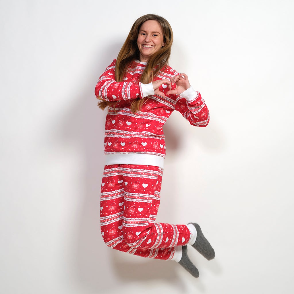 Una donna saltellante che indossa un pigiama rosso con un motivo a cuore.