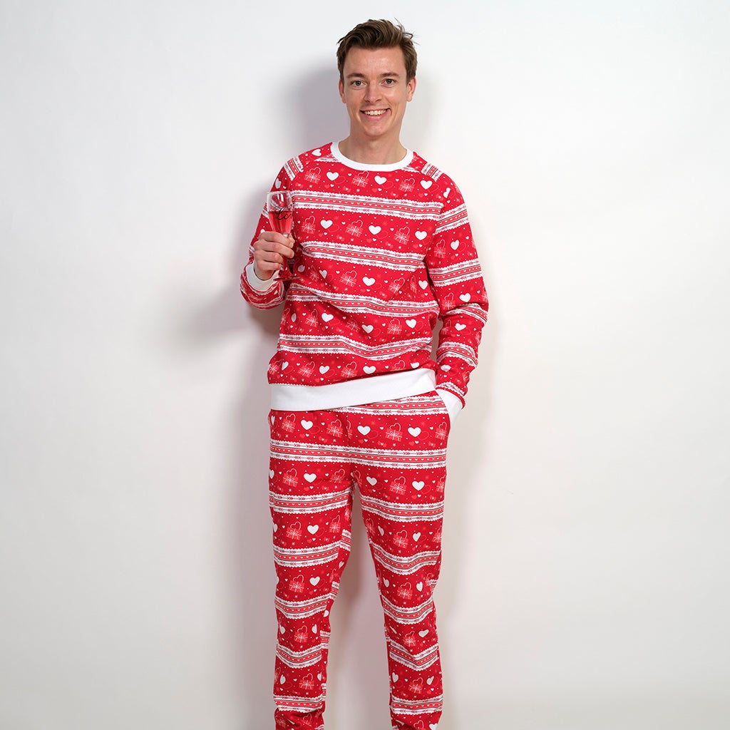 Un uomo sorridente che indossa un pigiama rosso con un motivo a cuore.